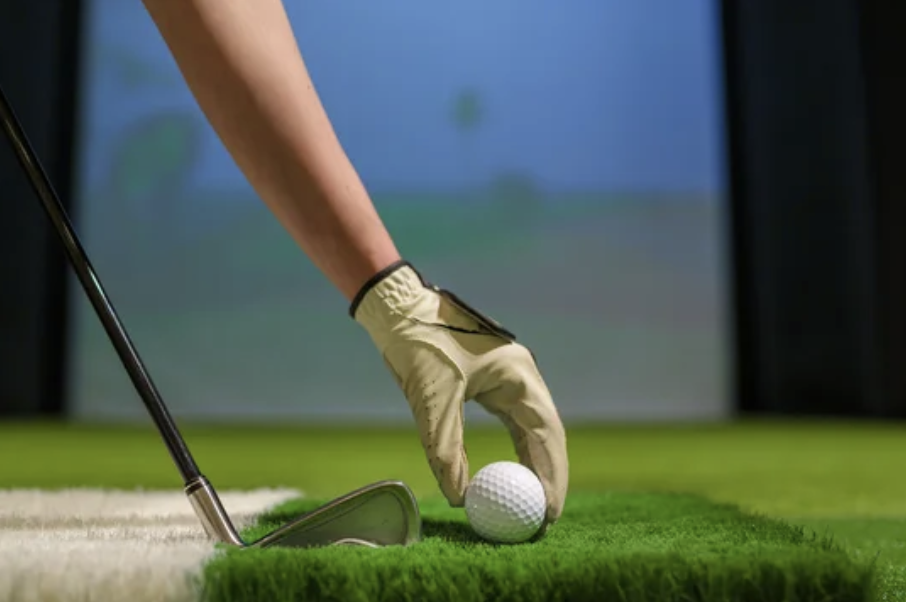 Golfer placing ball on simulator mat